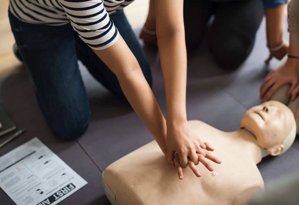 en femme s'entrainant aux gestes de premiers secours sur un mannequin de secourisme