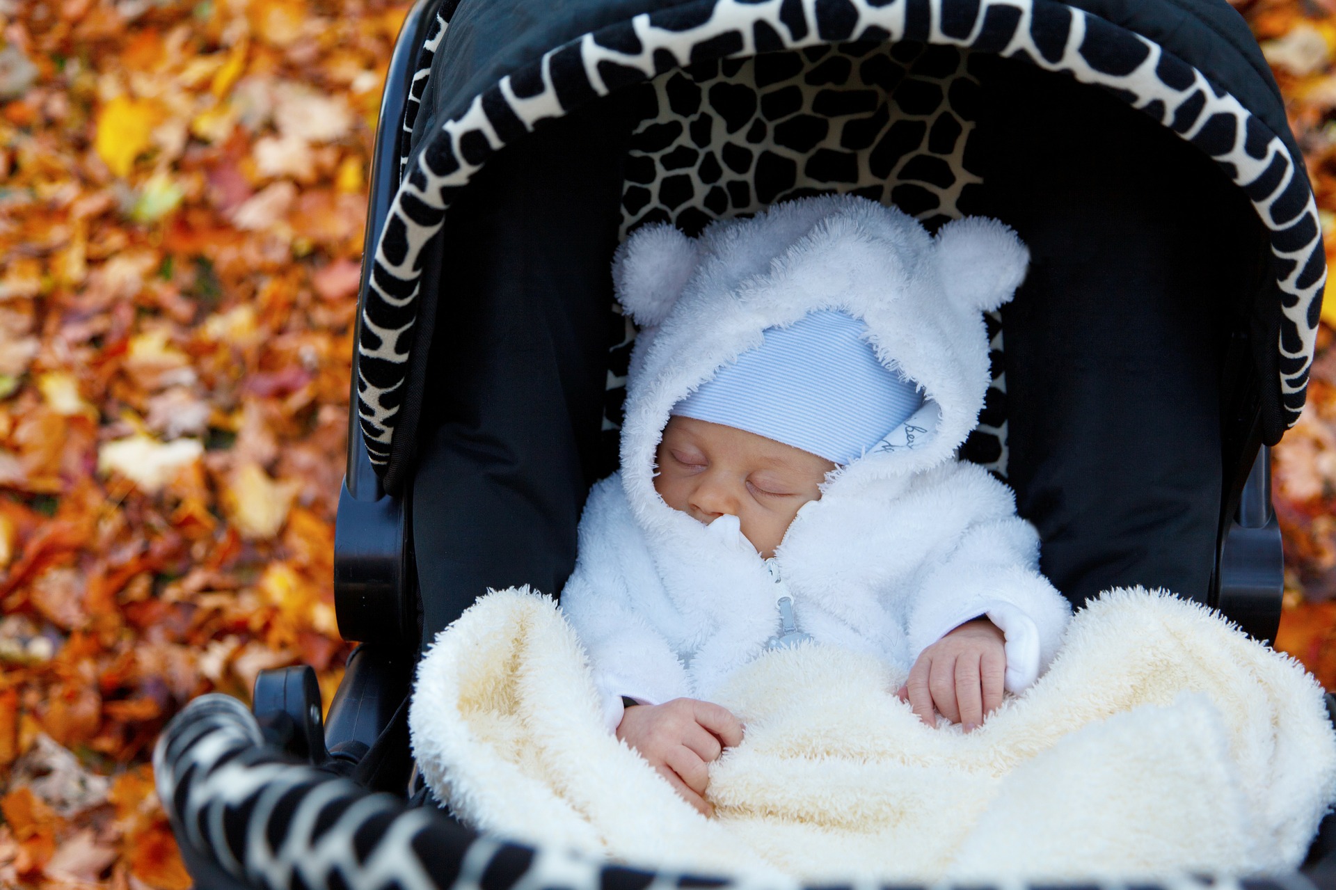 un bébé avec un manteau blanc qui dort dans une poussette