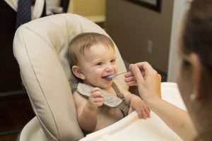 petit enfant dans un chaise haute qu'on fait manger