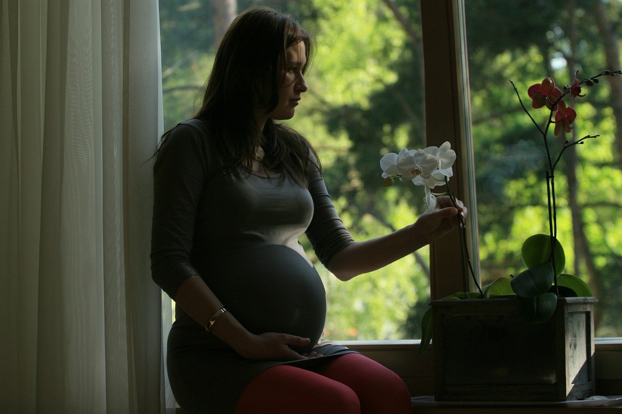 femme enceinte assise qui tient une fleur